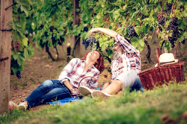 Mooie vrolijke paar plezier op picknick bij een wijngaard.