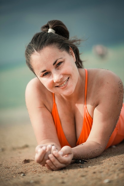 Mooie vrouw 40 jaar oud plus size, op het strand in een oranje zwempak, body positivity-thema