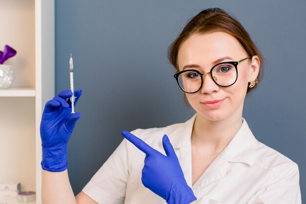 Mooie vrouw arts cosmetologist met spuit voor schoonheidsinjecties. geïsoleerd vrouwelijk studioportret.