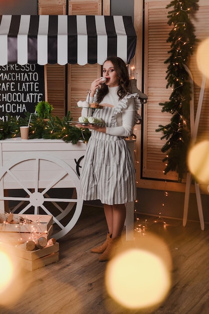 mooie vrouw barista in gestreepte schort houdt koffiekopje in de hand Nieuwjaar showcase