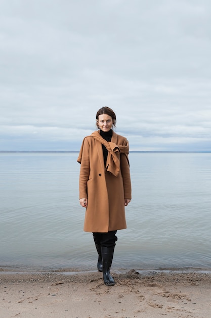 Mooie vrouw beige wollen jas dragen aan zee