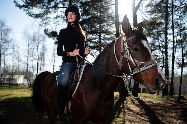 Mooie vrouw berijdt een paard met een helm op