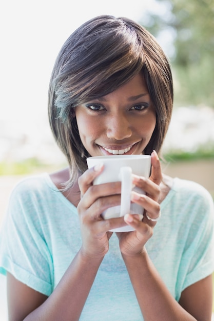 Mooie vrouw buiten zitten met koffie