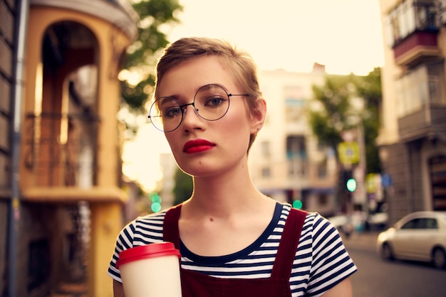 Mooie vrouw buitenshuis met glazen glas met drankje lopen