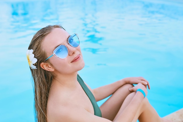 Mooie vrouw chillen bij het zwembad Zomerrecreatie reisconcept