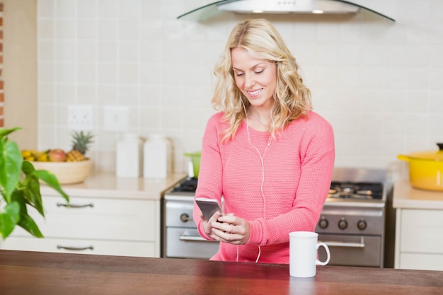 Mooie vrouw die aan muziek in de keuken luistert