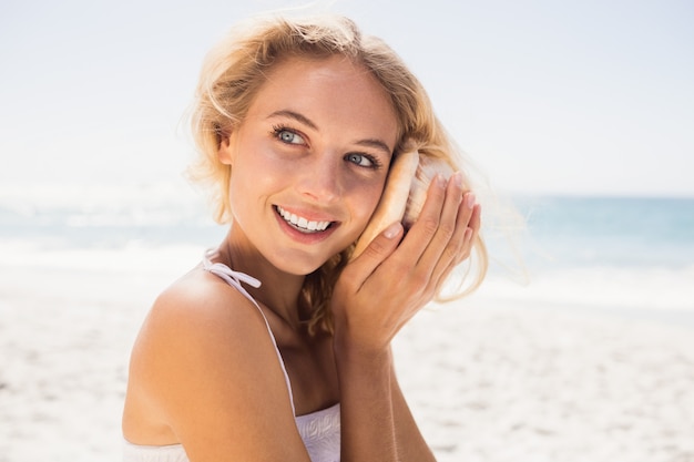 Mooie vrouw die aan shell luistert