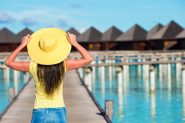 Mooie vrouw die aan waterbungalow bij tropische vakantie loopt