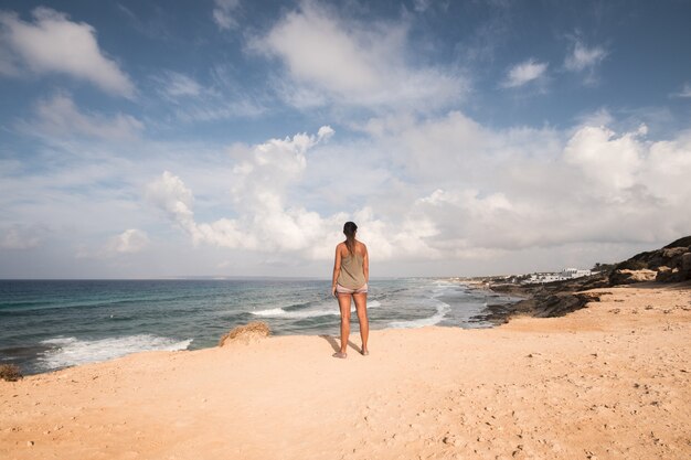 Mooie vrouw die aan zee staat en naar de horizon kijkt, met zijn rug naar de camera op een zonnige zomerdag. formentera-eiland. spanje.