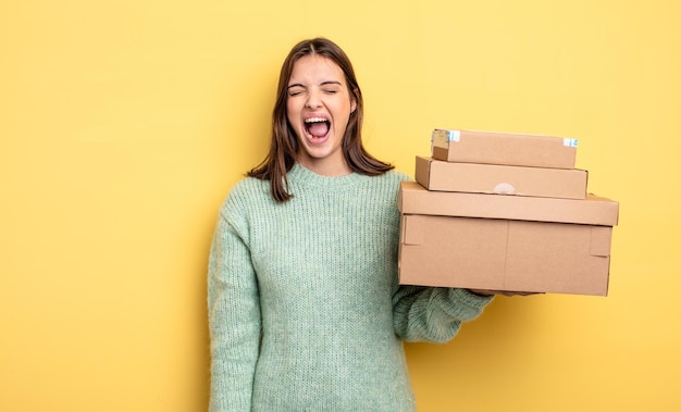 Mooie vrouw die agressief schreeuwt, op zoek naar een heel boos concept van pakketdozen