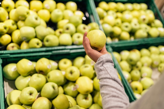 Mooie vrouw die appels in supermarkt kiest. Marktvoedselconcept.