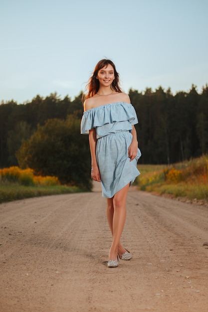 Mooie vrouw die bij de landweg in zonsondergang lopen