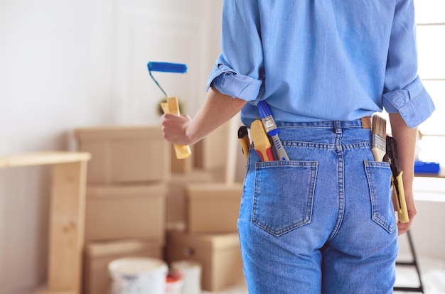 Mooie vrouw die binnenmuur van huis schildert met verfroller