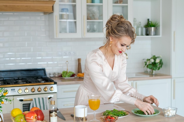 Mooie vrouw die biologische vegetarische salade kookt en aardbeien snijdt