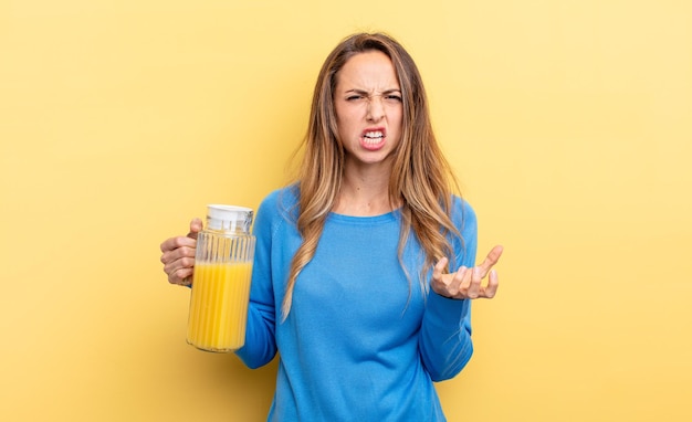 Mooie vrouw die boos, geïrriteerd en gefrustreerd sinaasappelsapconcept kijkt