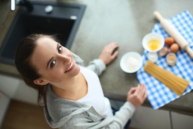 Mooie vrouw die cake kookt in de keuken die bij het bureau staat