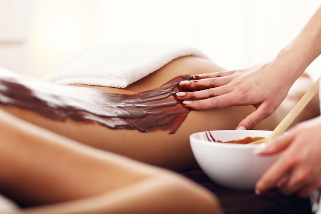 Mooie vrouw die chocolademassage krijgt in spa