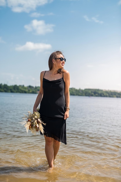 Mooie vrouw die cocktail zwarte kleding draagt die zich op watermeer bevindt
