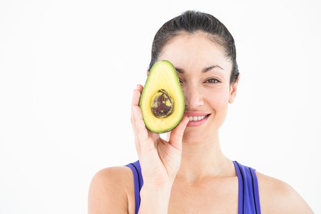 Mooie vrouw die de helft van een avocado toont