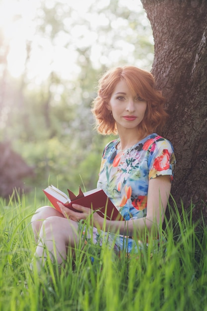 Mooie vrouw die een boek in de de lentetuin leest