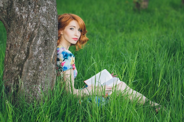 Mooie vrouw die een boek in de de lentetuin leest