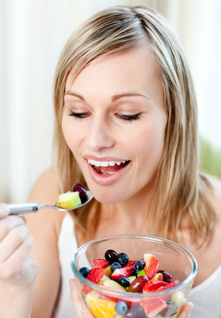 Mooie vrouw die een fruitsalade eet