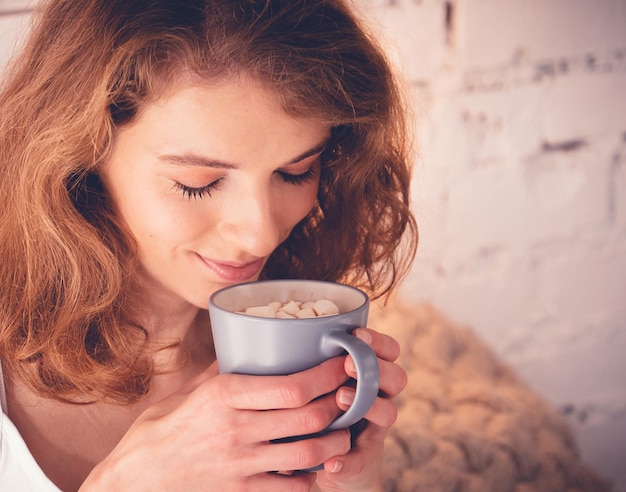 Mooie vrouw die een kopje koffie drinkt in haar bed Lifestyle concept