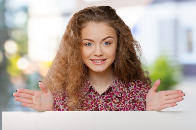 Mooie vrouw die een leeg aanplakbord houdt