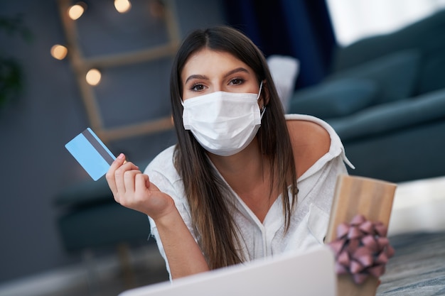 mooie vrouw die een masker draagt dat online met creditcard winkelt