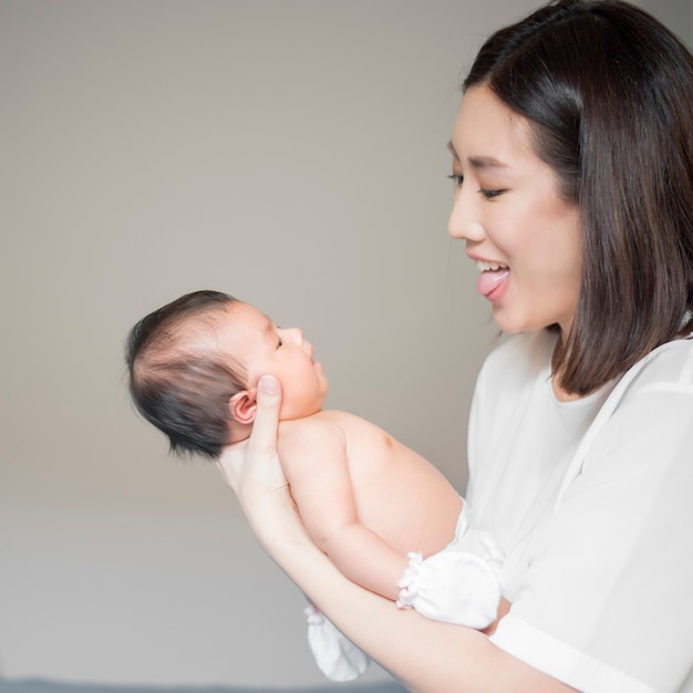 Mooie vrouw die een pasgeboren baby in haar wapens houdt