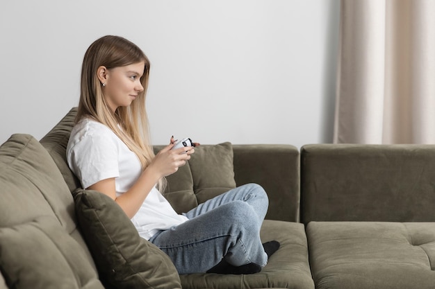 Mooie vrouw die gameconsole speelt terwijl ze op de bank zit