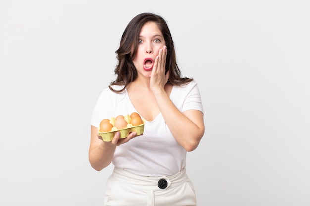 Mooie vrouw die geschokt en bang is en een eierdoos vasthoudt