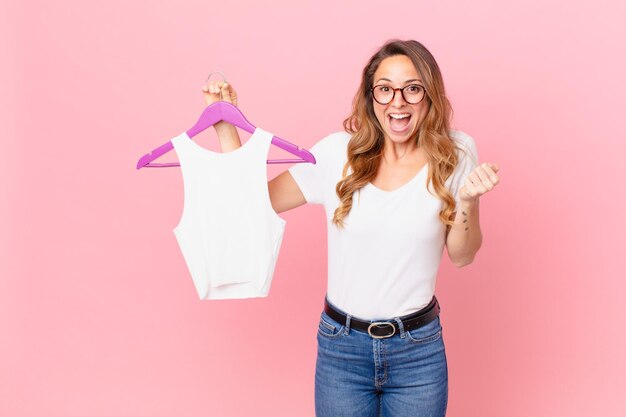 Mooie vrouw die geschokt is, lacht en succes viert en kleding kiest