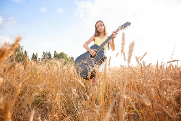 Mooie vrouw die gitaar speelt op het veld.