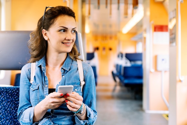 Mooie vrouw die haar mobiel in de trein gebruikt.