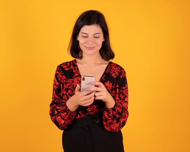 Mooie vrouw die haar smarpthone, gele ruimte gebruiken