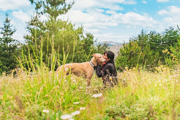 Mooie vrouw die haar windhondhond in openlucht kust