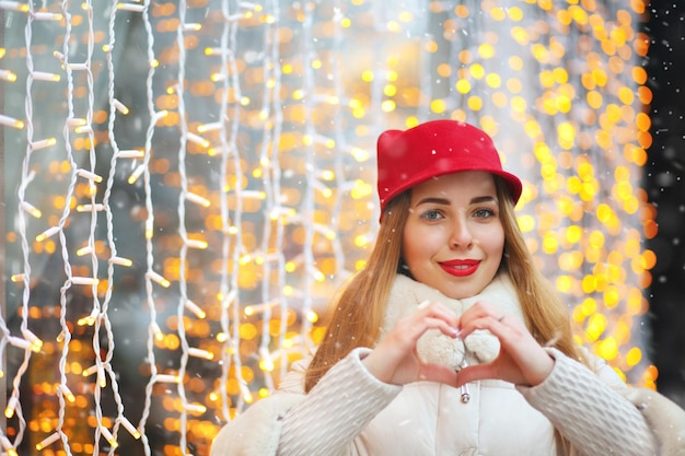 Mooie vrouw die hartgymbol toont tegen bokehachtergrond. Lege ruimte