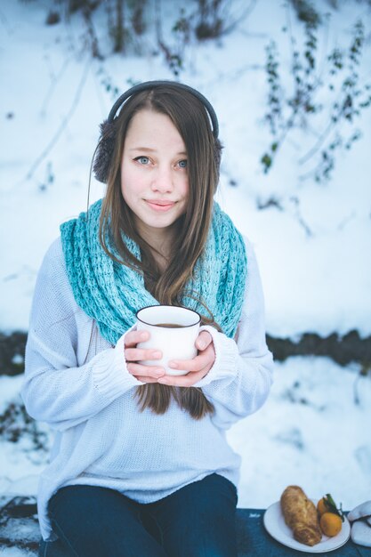 Mooie vrouw die hete drank in de winterpark drinkt