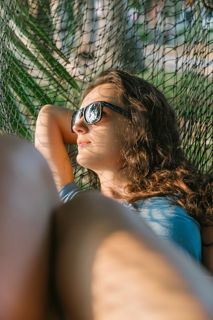 Mooie vrouw die in hangmat dichtbij de oceaan ligt.