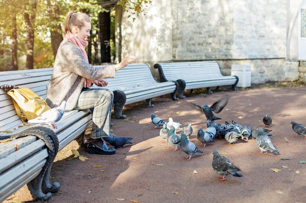 Mooie vrouw die in het park rust en duiven voert