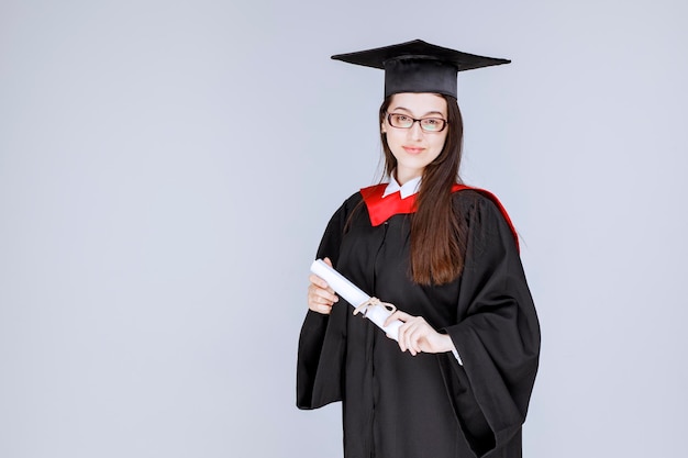 Mooie vrouw die in toga haar universiteitsdiploma houdt. Hoge kwaliteit foto