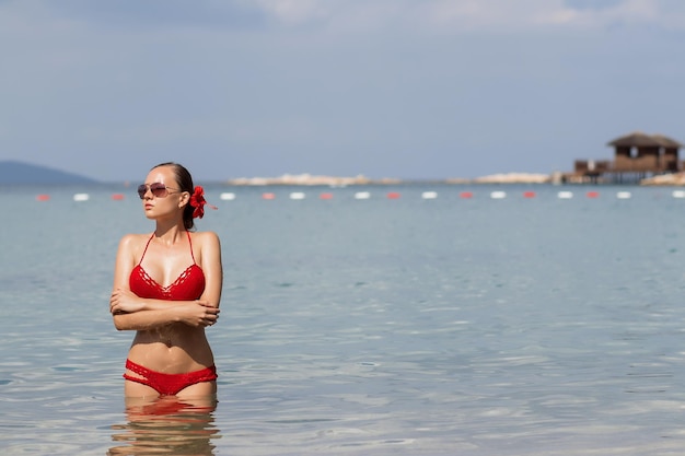 Mooie vrouw die in zeewater loopt Mooie jonge dame in rode gebreide badkleding die wegkijkt