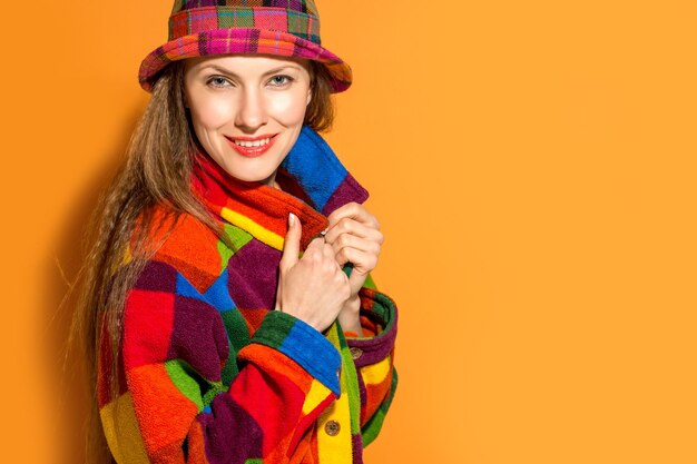 Mooie vrouw die kleurenkleding draagt over oranje backround