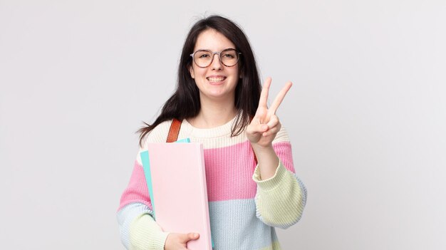 Mooie vrouw die lacht en er gelukkig uitziet, gebarend naar overwinning of vrede. universitair studentenconcept