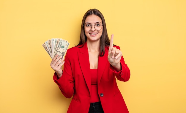 Mooie vrouw die lacht en er vriendelijk uitziet met het concept van nummer één dollarbankbiljetten