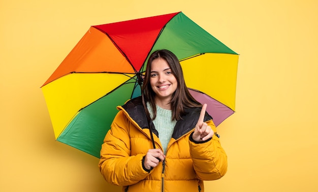 Mooie vrouw die lacht en er vriendelijk uitziet met het nummer één winter- en parapluconcept