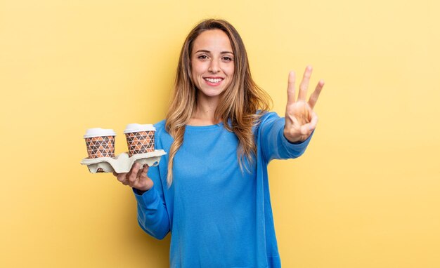 Mooie vrouw die lacht en er vriendelijk uitziet, met nummer drie. afhaal koffie concept