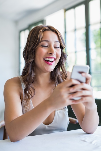 Mooie vrouw die lacht tijdens het gebruik van haar mobiele telefoon