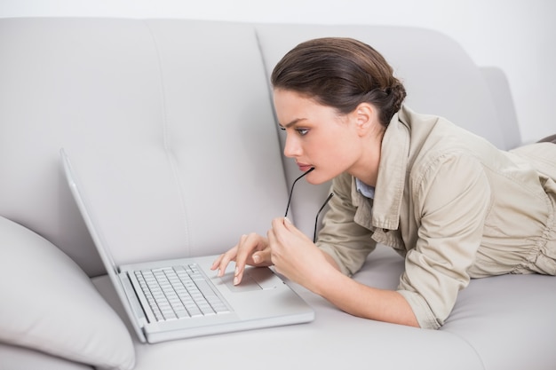 Mooie vrouw die laptop op bank thuis met behulp van